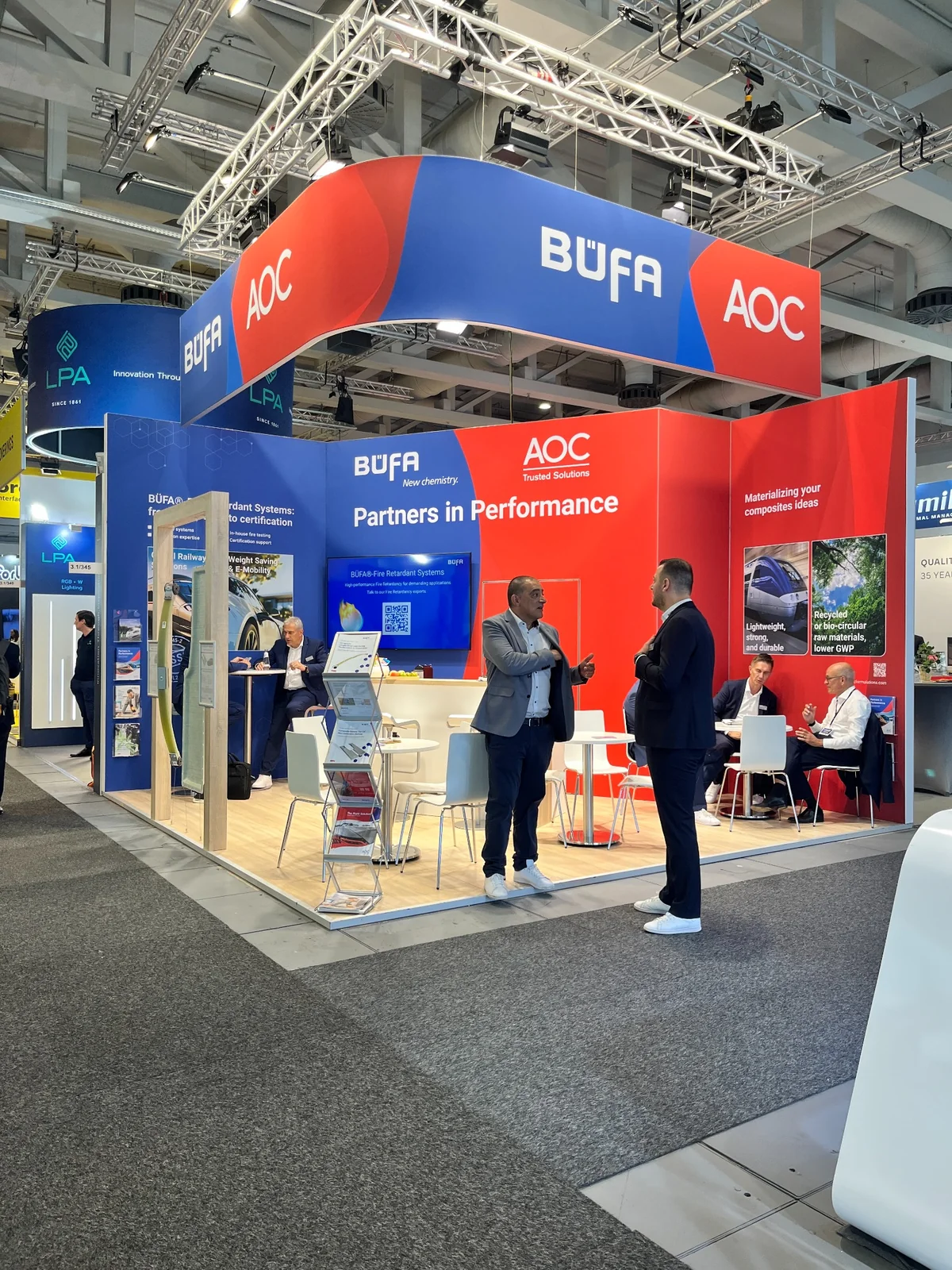The blue and red B&Uuml;FA and AOC exhibition stand with visitors at InnoTrans 2026.